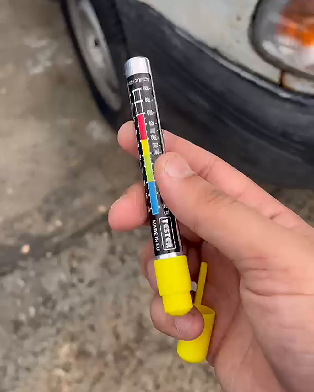 Paint tester pen in hand, next to a real car